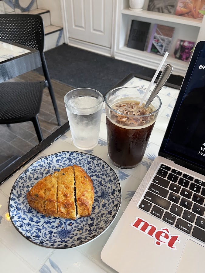 Iced coffee and pastry on cafe table beside laptop