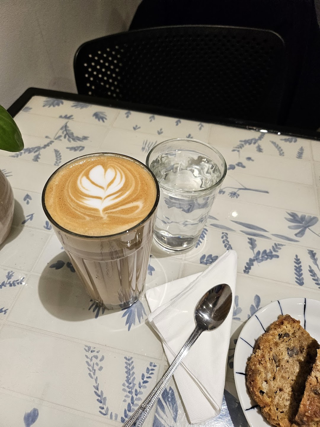 Latte with latte art, water, and pastry at Moments